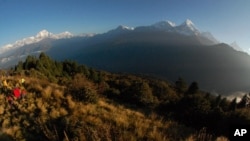 Para pendaki menyaksikan matahari terbit di Pegunungan Annapurna (kanan) di Nepal tengah. 