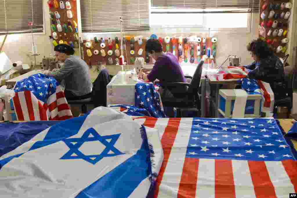 Beberapa orang menjahit bendera Israel dan bendera AS di kota Kfar Saba, sebagai persiapan untuk menyambut kunjungan Presiden AS Barack Obama. Presiden Obama akan melakukan kunjungan tiga hari ke Israel dan Palestina mulai tanggal 20 Maret.