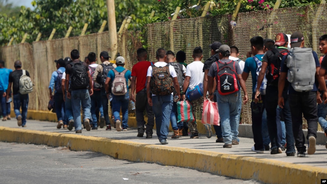 FILE - Central American migrants cross into Mexico from Guatemala, near Ciudad Hidalgo, Mexico, June 4, 2019. The migrants walked over the bridge and waited to register at a Mexican immigration office.