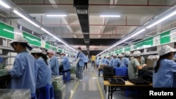 中国广东东莞的工人为一家美国公司的RiotPWR移动游戏控制器在生产线上工作。（2021年12月7日）