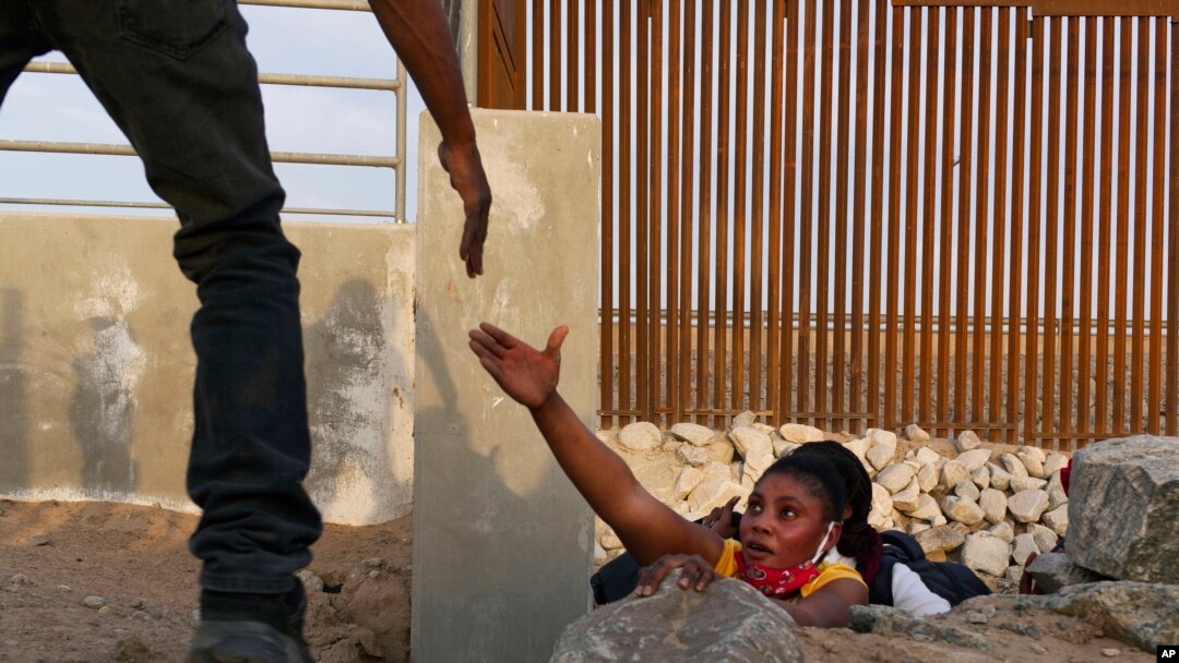 Foto Achiv: Yon migran Ayisyen mande asistans apre li soti nan yon kanal chaje ak woch ki bo kote fwontye Etazini nan Yuma, Arizona, 9 Jyen 2021. 
