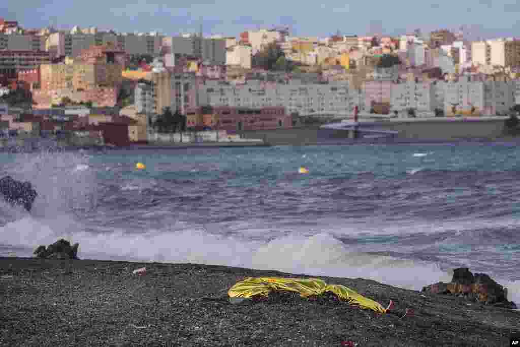 The body of a young man is seen covered with an emergency blanket after being recovered by Spanish police from waters near the border between Morocco and Spain's north African enclave of Ceuta.