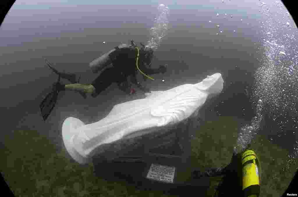 A diver from the diving school "Dive Nicaragua" takes pictures of a statue of the Miraculous Medal Virgin after it was buried in the deep sea at San Juan del Sur town, Nicaragua, Oct. 8,2016.