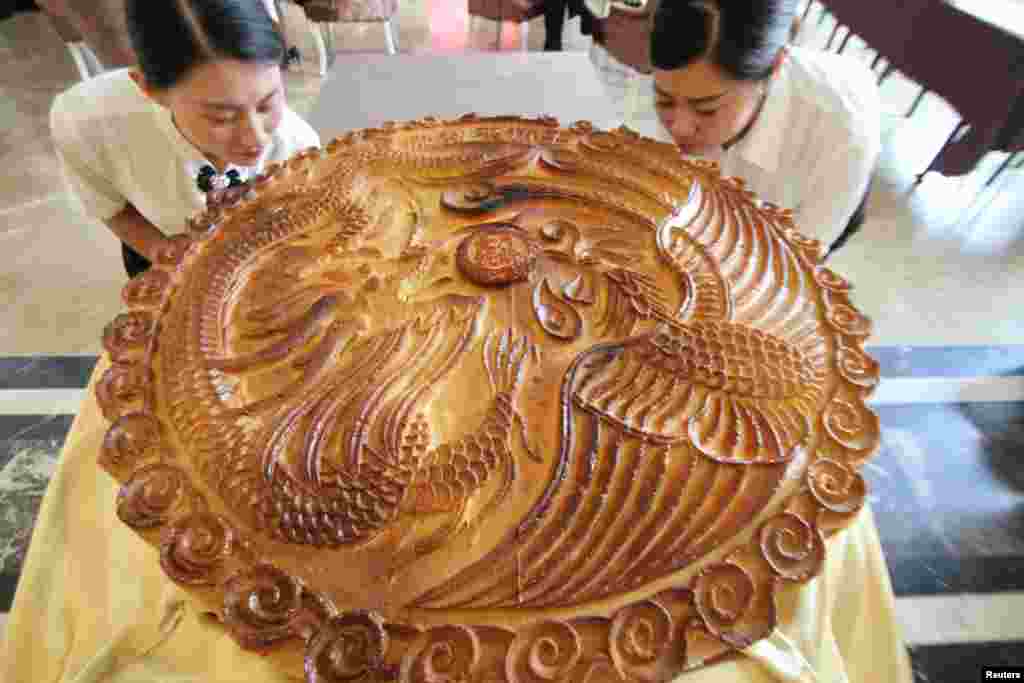 Staff pose with a giant moon cake ahead of China's Mid Autumn Festival in Binzhou, Shandong Province, China, Sept. 10, 2016.
