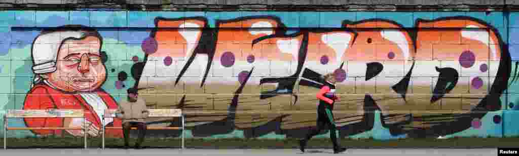 Seorang pelari berlari melewati grafiti pada hari musim semi yang cerah di kota Wina, Austria.