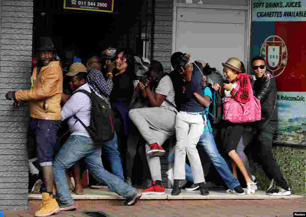 Para mahasiswa Universitas Witwatersrand yang menuntut biaya kuliah gratis menghindari tembakan peluru karet polisi anti huru-hara dalam demonstrasi di Johannesburg, Afrika Selatan.