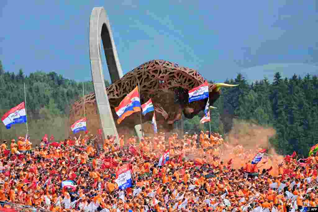 Supporters of Red Bull's Dutch driver Max Verstappen cheer from the stands near the large-scale jumping bull sculpture during the Formula One Austrian Grand Prix at the Red Bull Ring race track in Spielberg, Austria.