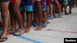 Niños migrantes venezolanos hacen fila dentro de un coliseo donde se instaló un campamento temporal en Arauquita, Colombia, el 26 de marzo de 2021.