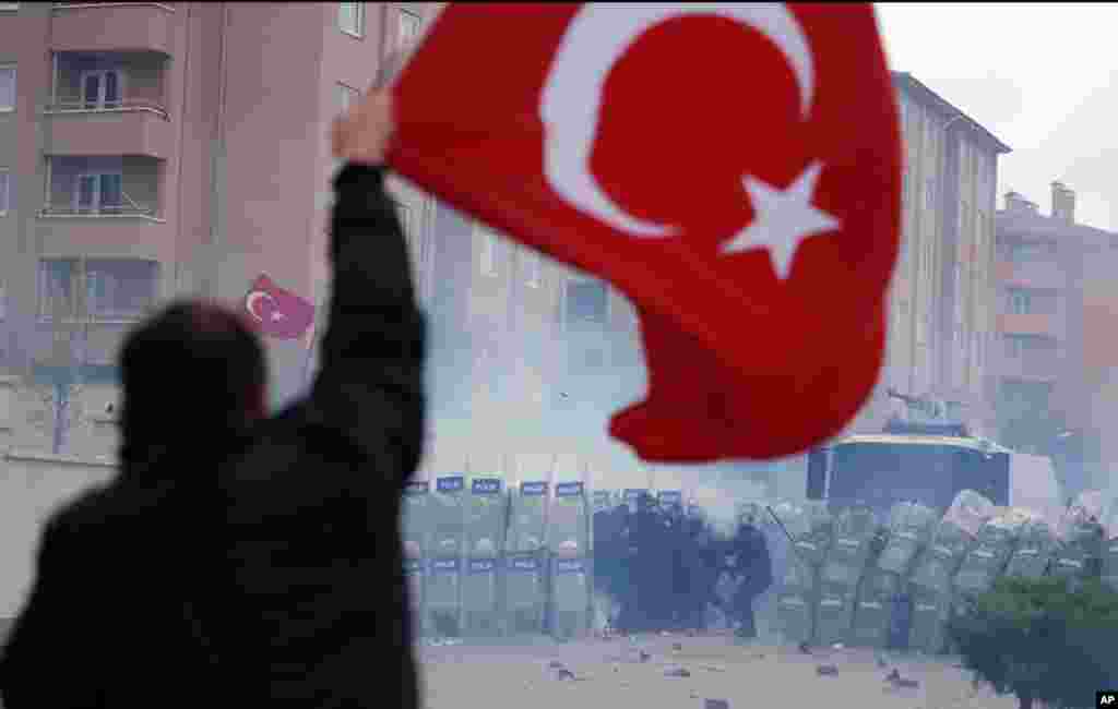 Seorang pria, memegang bendera nasional Turki, saat ribuan demonstran bentrok dengan pasukan keamanan ketika mereka mencoba menerobos barikade di sekitar penjara dan gedung pengadilan di kota Silivri, di pinggiran Istanbul.