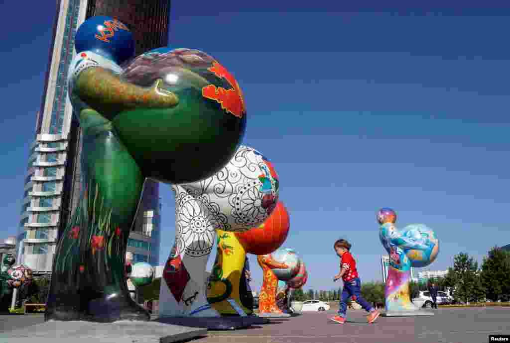 A boy runs past figures symbolizing countries participating in Expo 2017 at downtown of Astana, Kazakhstan. Astana will host the exhibition next year .