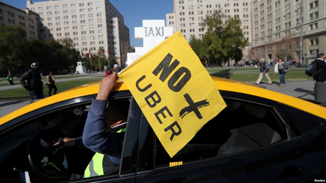 FILE - A taxi driver holds a flag reading "No more Uber" during a nationwide strike to protest against Uber Technologies in Santiago, Chile.