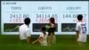 Passersby look at an electronic board displaying Topix, Japan's Nikkei share averages, and Japanese yen exchange rate against the U.S. dollar outside a brokerage in Tokyo, Japan, Aug. 6, 2024.