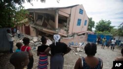 Warga di lokasi sekolah yang rusak akibat gempa berkekuatan 5,9 SR di Gros Morne, Haiti, 7 Oktober 2018. 