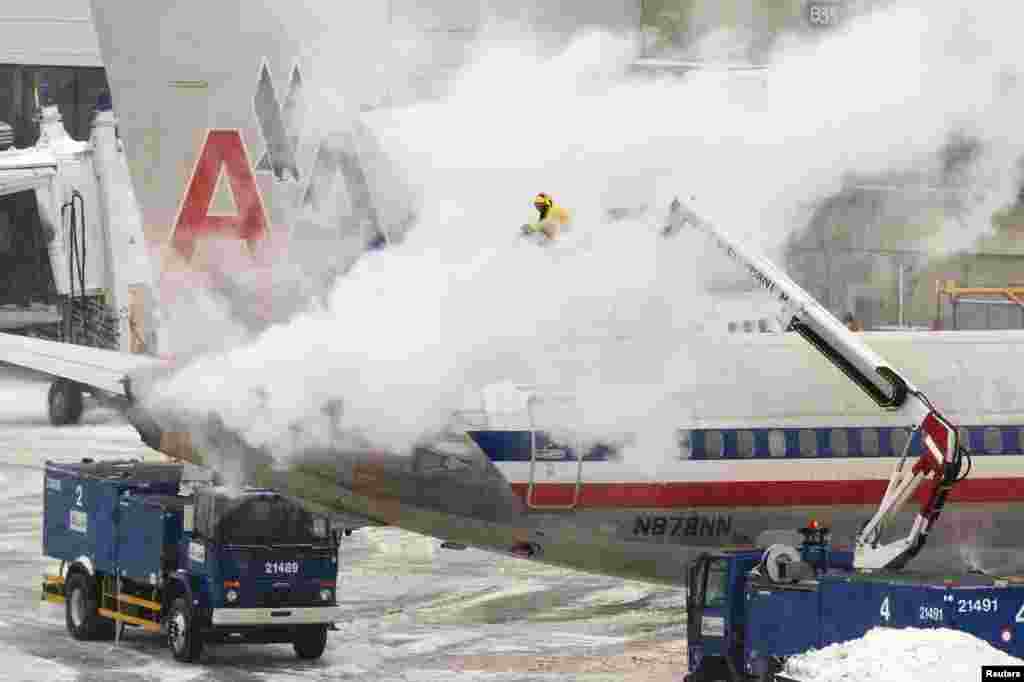 A equipa da American Airlines lança im spray descongelante para cima de um avião em Boston, Jan. 2, 2014.