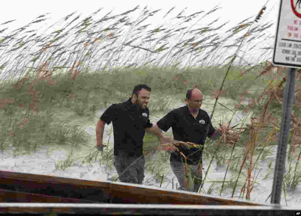 Dua pria berlari menghindari hujan menjelang datangnya Badai Matthew (6/10) di Pantai Jacksonville, Florida. (AP/John Bazemore)