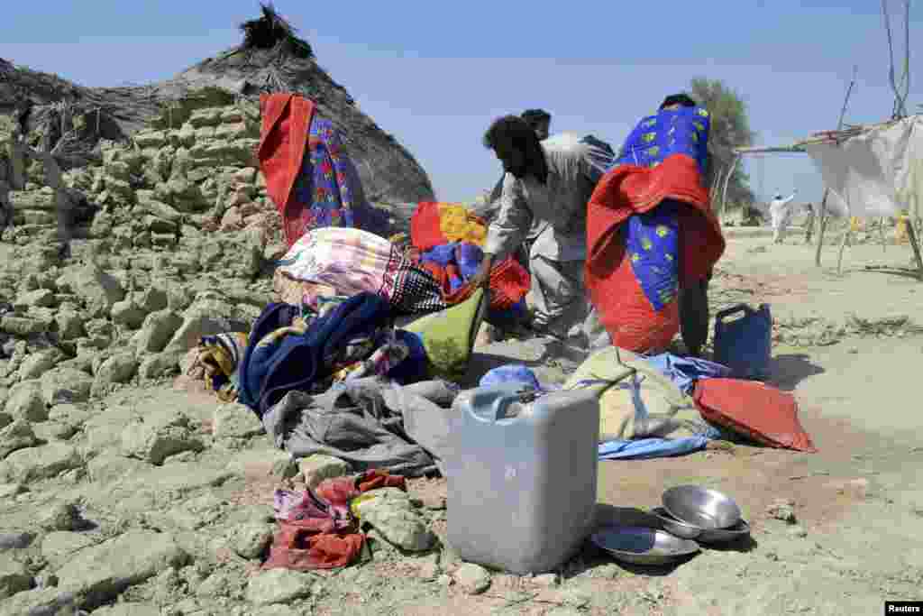 Survivors collect their belongings near the rubble of a mud house after it collapsed following an earthquake in the town of Awaran, southwestern Pakistani province of Baluchistan, Sept. 25, 2013. 