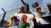 FILE - Demonstrators hold banners with the picture of Erol Onderoglu, local representative of Reporters Without Borders, during a protest against the arrest of three prominent activists for press freedom, in front of Metris prison in Istanbul, Turkey, June 24, 2016.