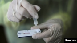 FILE - A health care worker holds a rapid COVID-19 antigen test at a coronavirus testing center in Nice, France, Oct. 15, 2020. Millions of such kits are heading to Africa for distribution.