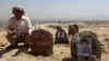FILE - An Afghan man prays in front graves of victims of a suicide attack, in Kabul, Afghanistan, July 25, 2016. 