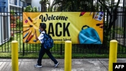 Un estudiante usa una máscara cuando ingresa a la escuela de St. Lawrence el primer día de clases después de las vacaciones de verano en el norte de Miami, el 18 de agosto de 2021.