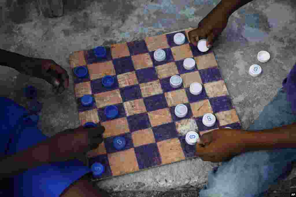Boys play checkers with bottle caps on a homemade board in the Philanthrope neighborhood of Les Cayes, Haiti after many homes lost their roofs and others in the seaside fishing community were completely destroyed.