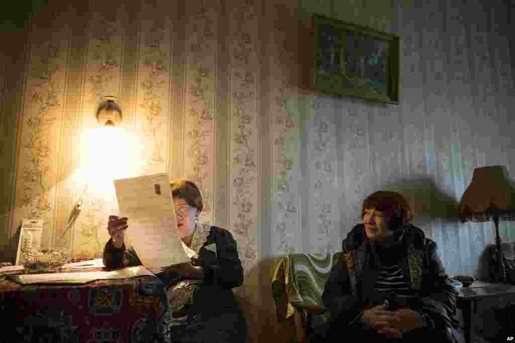 Ludmila Ezhova, 80, left, prepares to cast her ballot brought by an election official during a parliamentary election in Moscow, Russia.