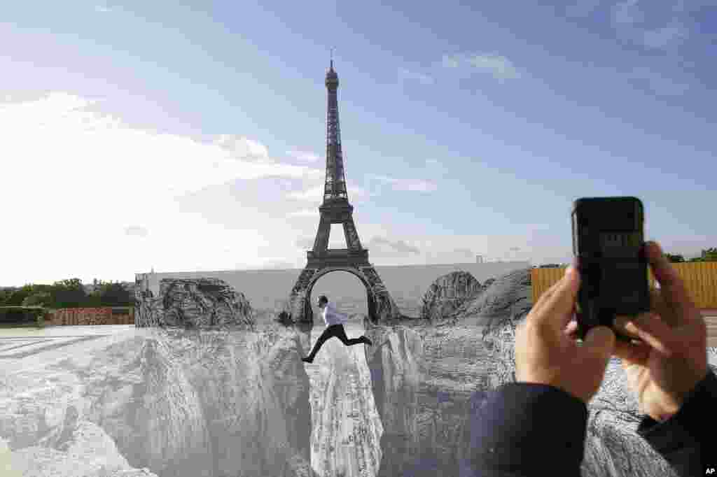 A man jumps on the Trocadero square in front of the Eiffel Tower, where the French artist and photographer known as JR set his artwork, in Paris.
